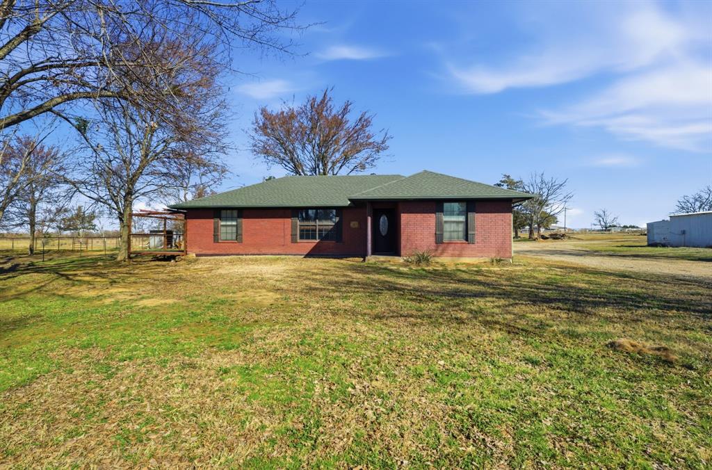 697 County Road 166 Whitesboro, TX 76273 - Photo 1 of 32 a front view of a house with a garden