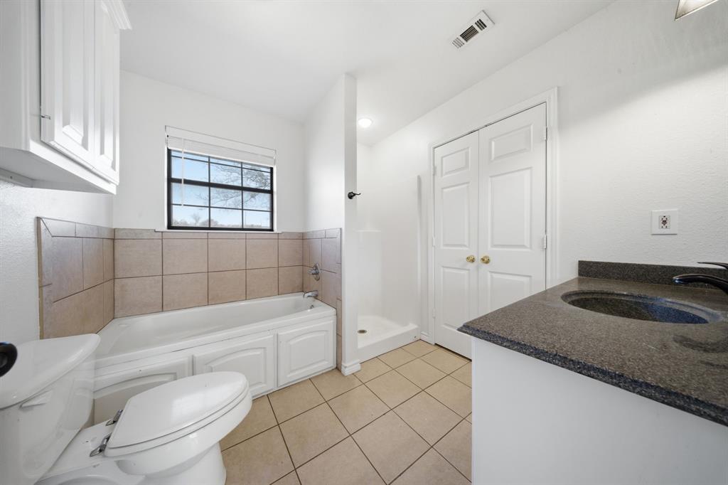 697 County Road 166 Whitesboro, TX 76273 - Photo 12 of 32 a bathroom with a granite countertop sink a toilet and bathtub