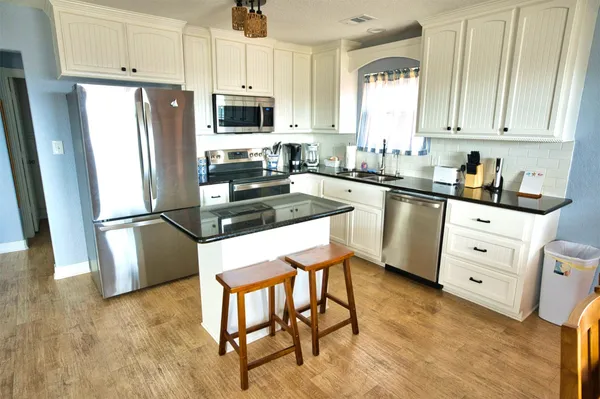 a kitchen with stainless steel appliances a refrigerator stove microwave and white cabinets