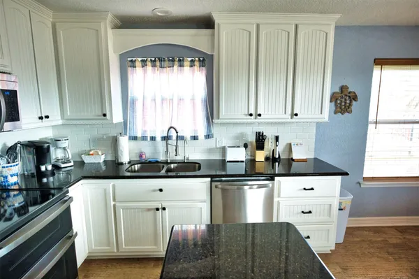 a kitchen with stainless steel appliances white cabinets and a window