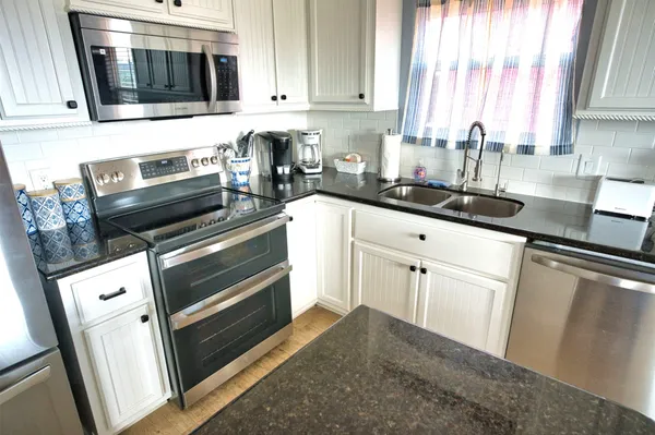 a kitchen with granite countertop cabinets stainless steel appliances and window