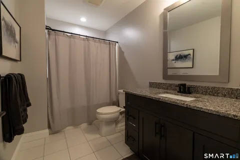 a bathroom with a granite countertop sink a toilet a mirror and vanity