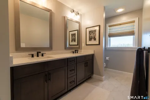 a bathroom with double vanity sink two mirror and a window