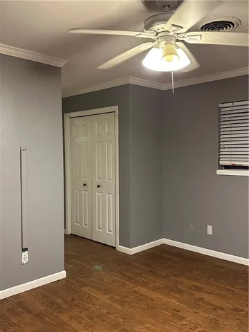 an empty room with wooden floor and chandelier fan