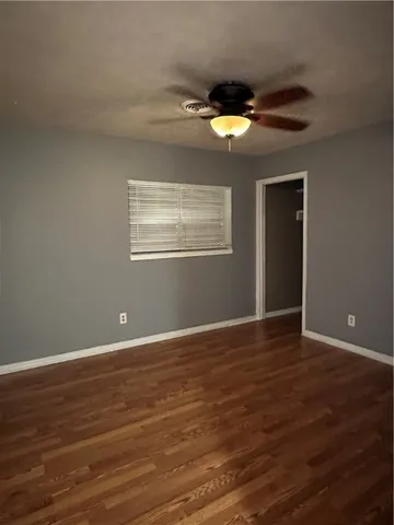 a view of an empty room with window and wooden floor
