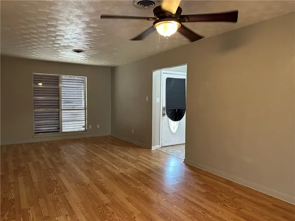 an empty room with wooden floor and windows