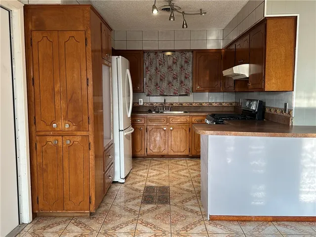 a kitchen with stainless steel appliances granite countertop a refrigerator a stove and a sink