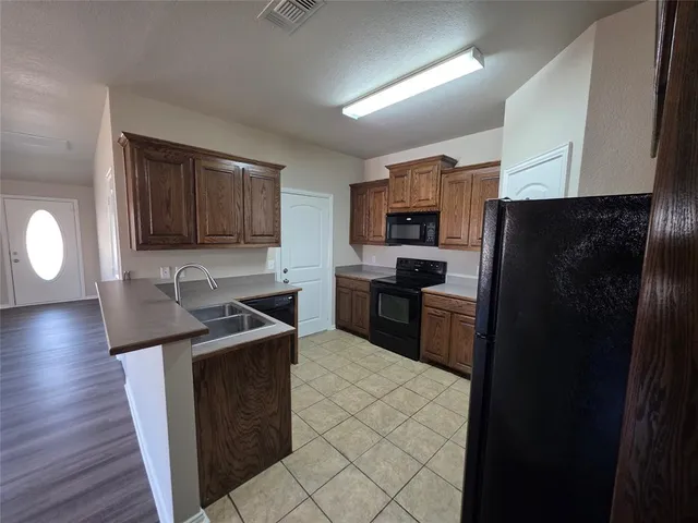 a kitchen with granite countertop a refrigerator stove and sink