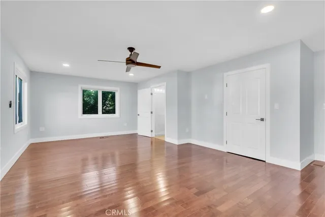 a view of an empty room with a window and wooden floor