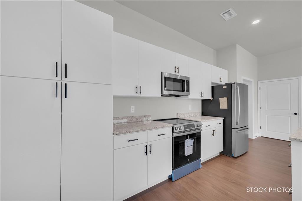 1038 Homestead Way Street Dacula, GA 30019 - Photo 11 of 36 a kitchen with stainless steel appliances granite countertop a stove top oven a sink a refrigerator white cabinets and wooden floor