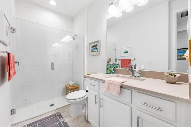 a bathroom with a granite countertop sink a toilet and shower