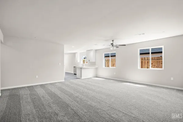 an empty room with windows and ceiling fan