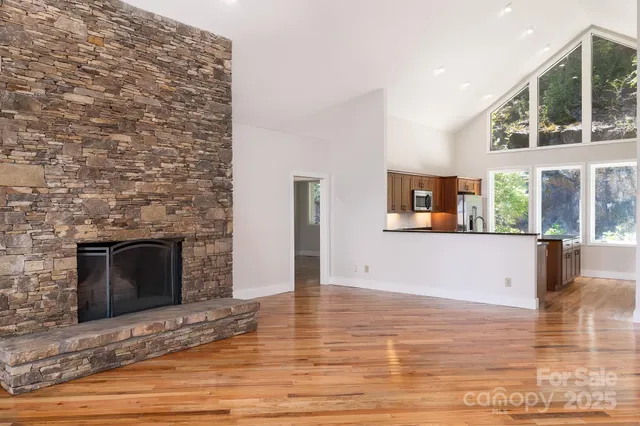 a view of an empty room with wooden floor and a fireplace