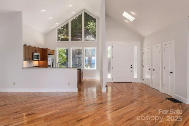 a view of an empty room with wooden floor and a window