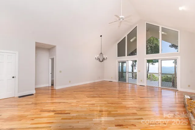 a view of an empty room with wooden floor and windows
