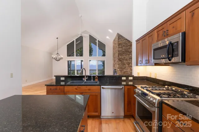 a kitchen with stainless steel appliances granite countertop a stove a sink and a microwave