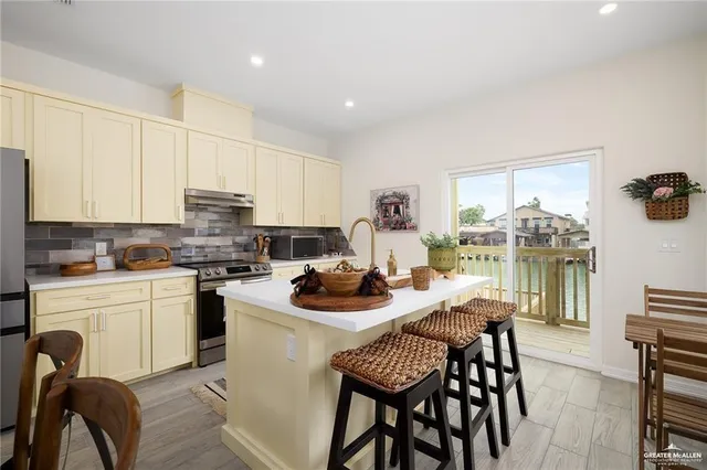a kitchen with stainless steel appliances kitchen island granite countertop a table chairs stove and white cabinets