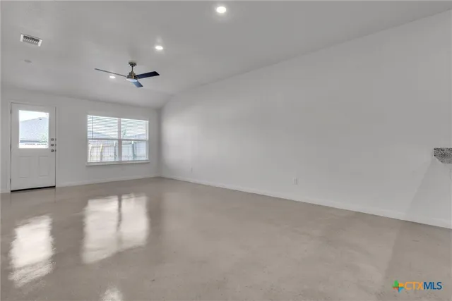 an empty room with windows and ceiling fan