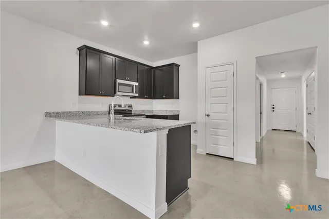 a kitchen with stainless steel appliances granite countertop a refrigerator and a stove top oven