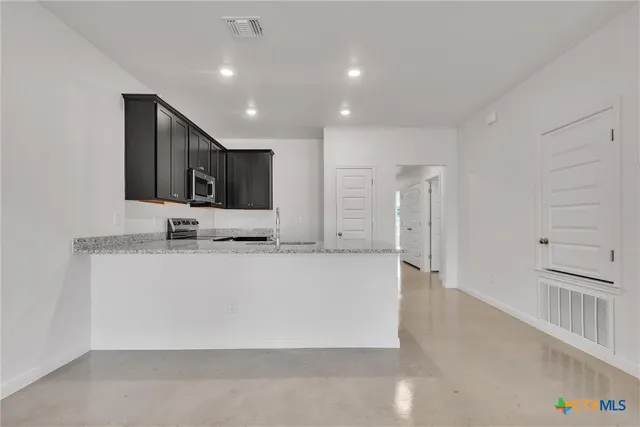 a large white kitchen with kitchen island a sink stainless steel appliances and cabinets