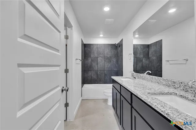 a bathroom with a granite countertop sink a toilet a mirror and bathtub