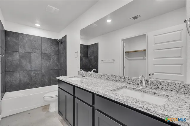 a bathroom with a granite countertop sink a toilet and bathtub
