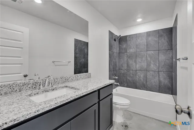 a bathroom with a granite countertop sink a toilet and bathtub