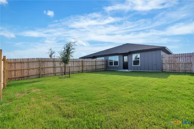 a view of a house next to a yard with wooden fence