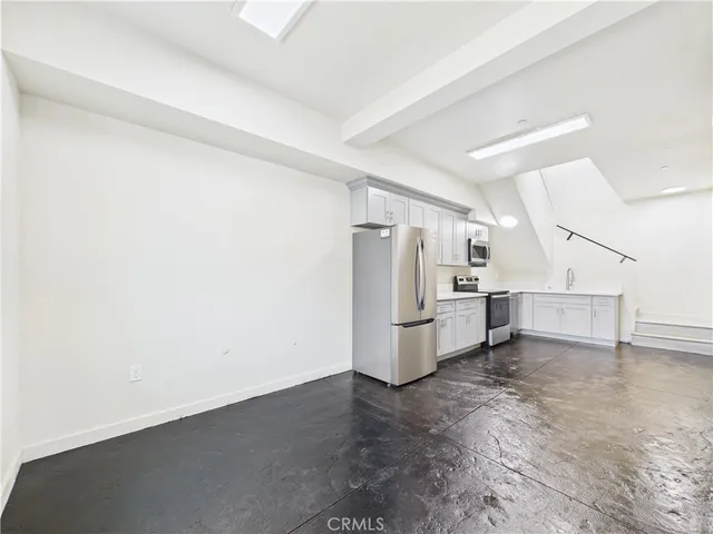 a view of a kitchen with refrigerator and white cabinets