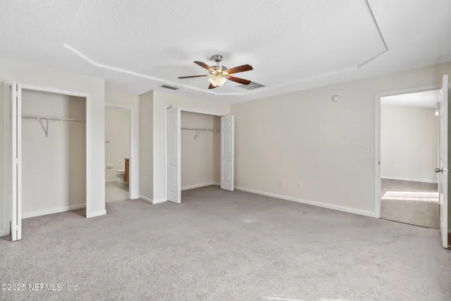 an empty room with closet and a ceiling fan