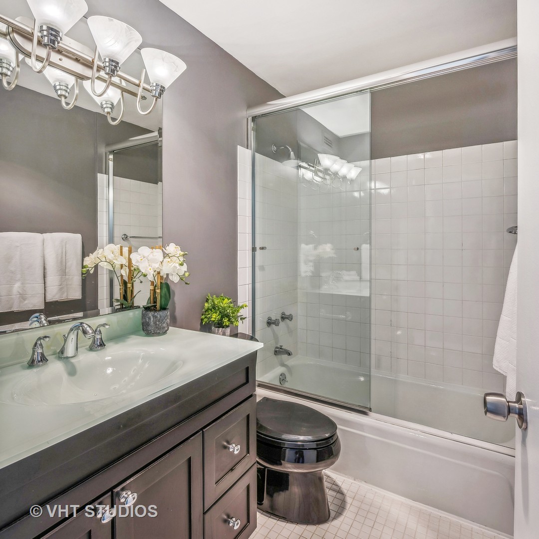 1850 North Clark Street, Unit 503 Chicago, IL 60614 - Photo 12 of 24 a bathroom with a granite countertop sink a toilet a mirror and shower