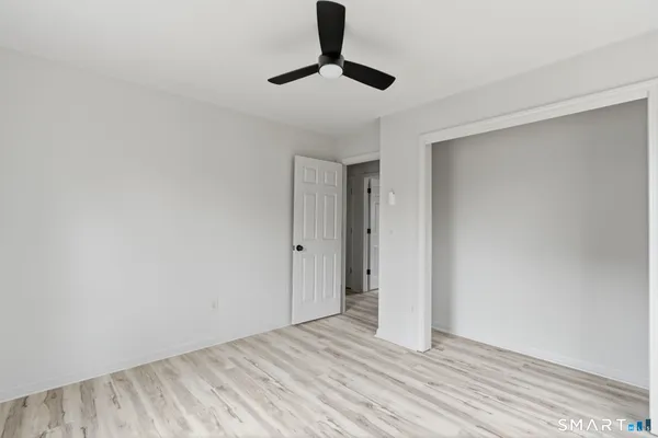 a view of empty room with wooden floor and fan