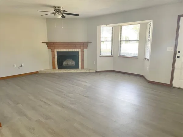 an empty room with windows fireplace and a sink