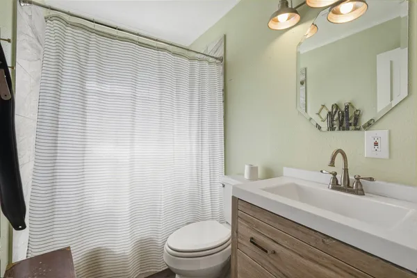 a bathroom with a sink a toilet a mirror and shower