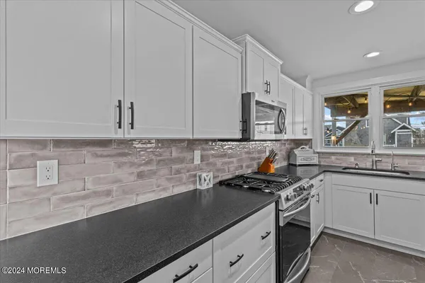 a kitchen with granite countertop a sink a stove and cabinets
