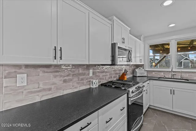 a kitchen with granite countertop a sink a stove and cabinets