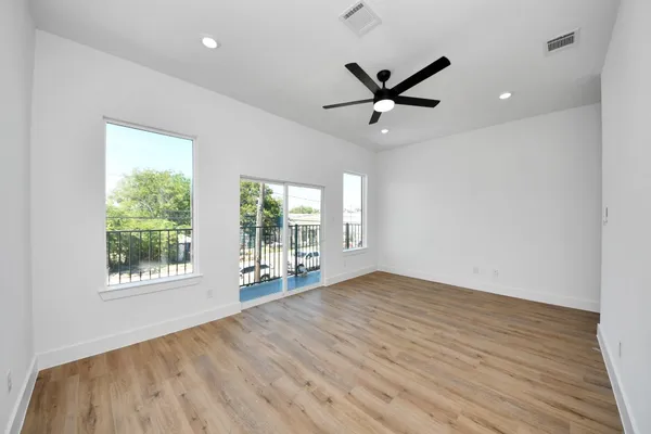 a view of an empty room with a window and wooden floor
