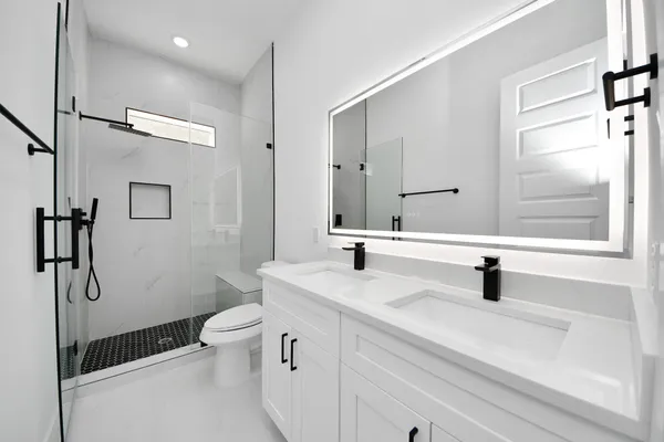 a bathroom with a sink a toilet a mirror and shower