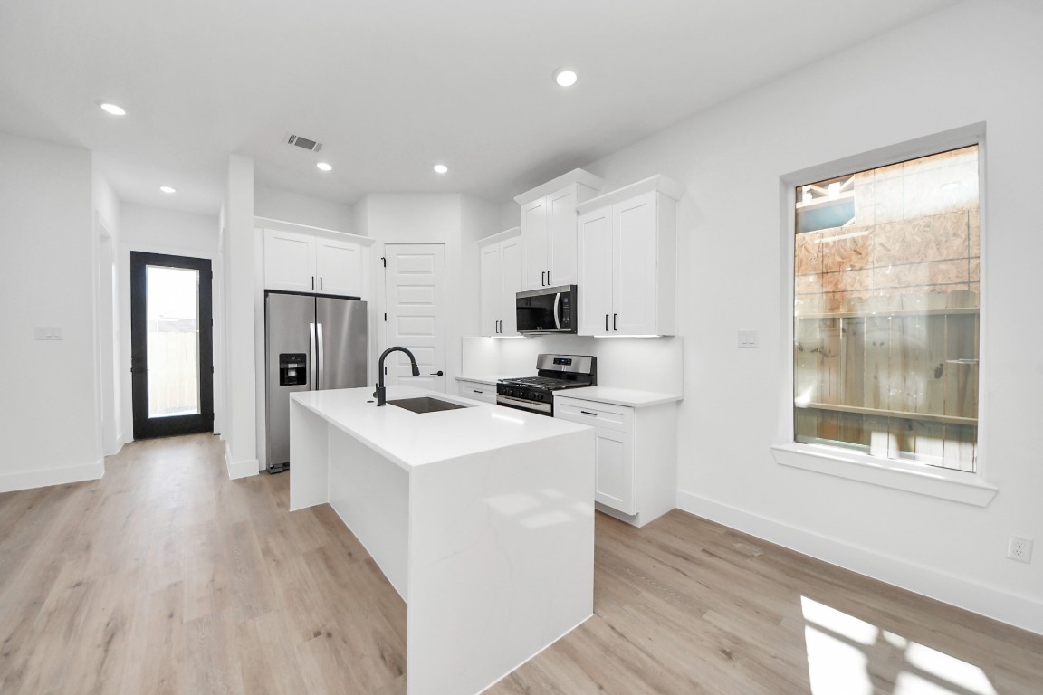 3310 Hardy Street Houston, TX 77009 - Photo 8 of 26 a kitchen with stainless steel appliances a refrigerator a sink dishwasher a stove and white cabinets with wooden floor