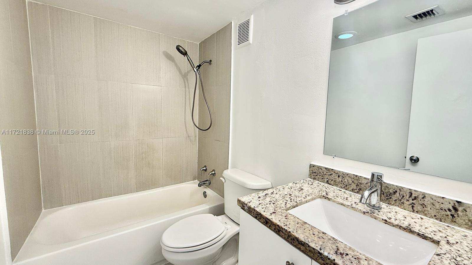 42 Southwest 14th Street, Unit 103 Dania Beach, FL 33004 - Photo 12 of 18 a bathroom with a granite countertop sink toilet mirror and shower