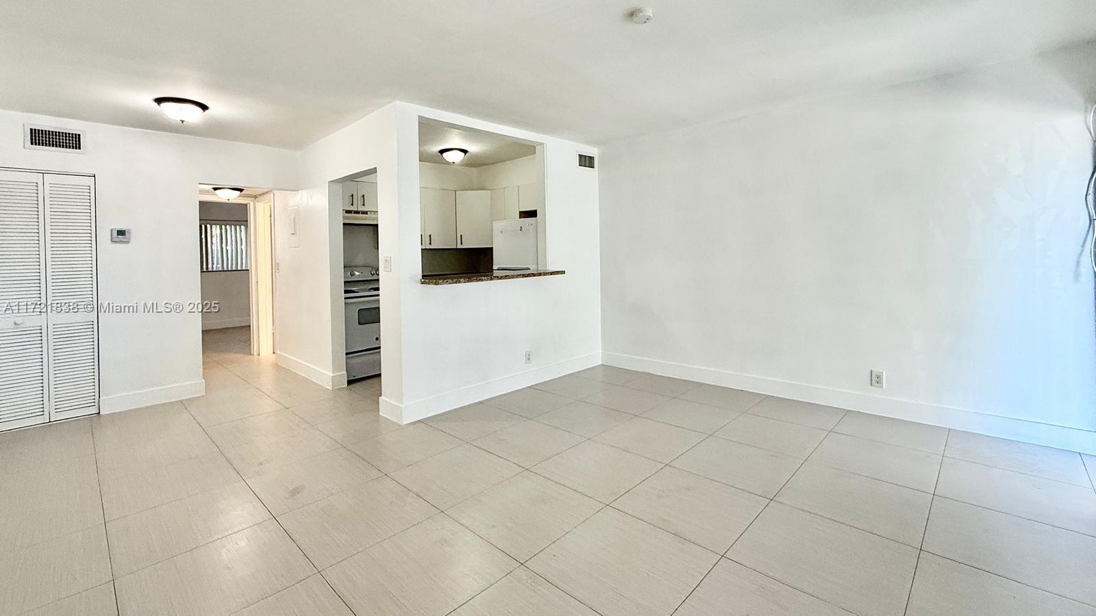 42 Southwest 14th Street, Unit 103 Dania Beach, FL 33004 - Photo 6 of 18 a view of a refrigerator in kitchen and white cabinets