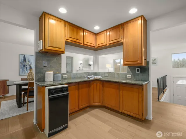 a kitchen with stainless steel appliances granite countertop wooden cabinets a sink and dishwasher a stove with wooden floor