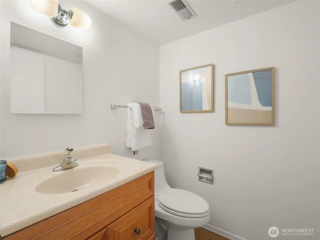 a bathroom with a toilet sink vanity and mirror