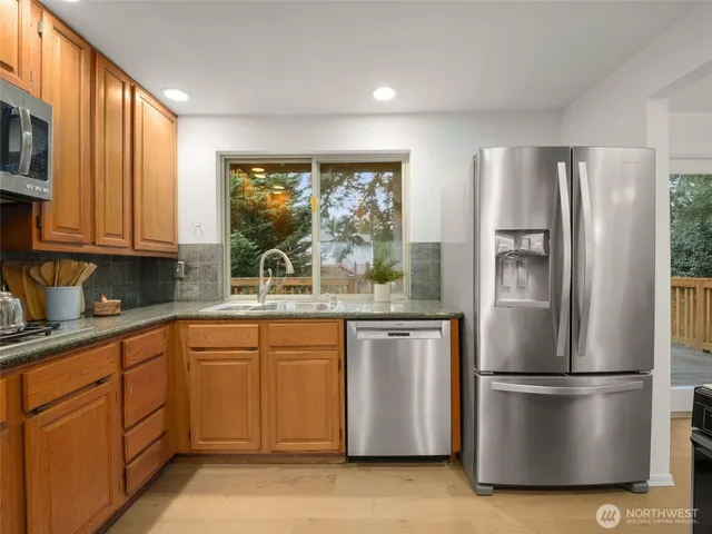 a kitchen with stainless steel appliances granite countertop a refrigerator a sink a stove and white cabinets