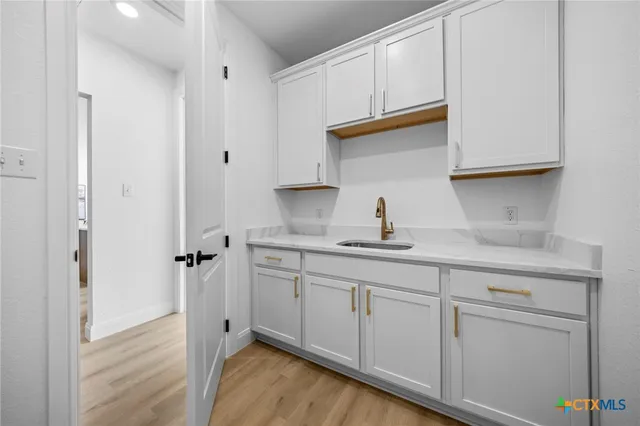 a kitchen with white cabinets and sink