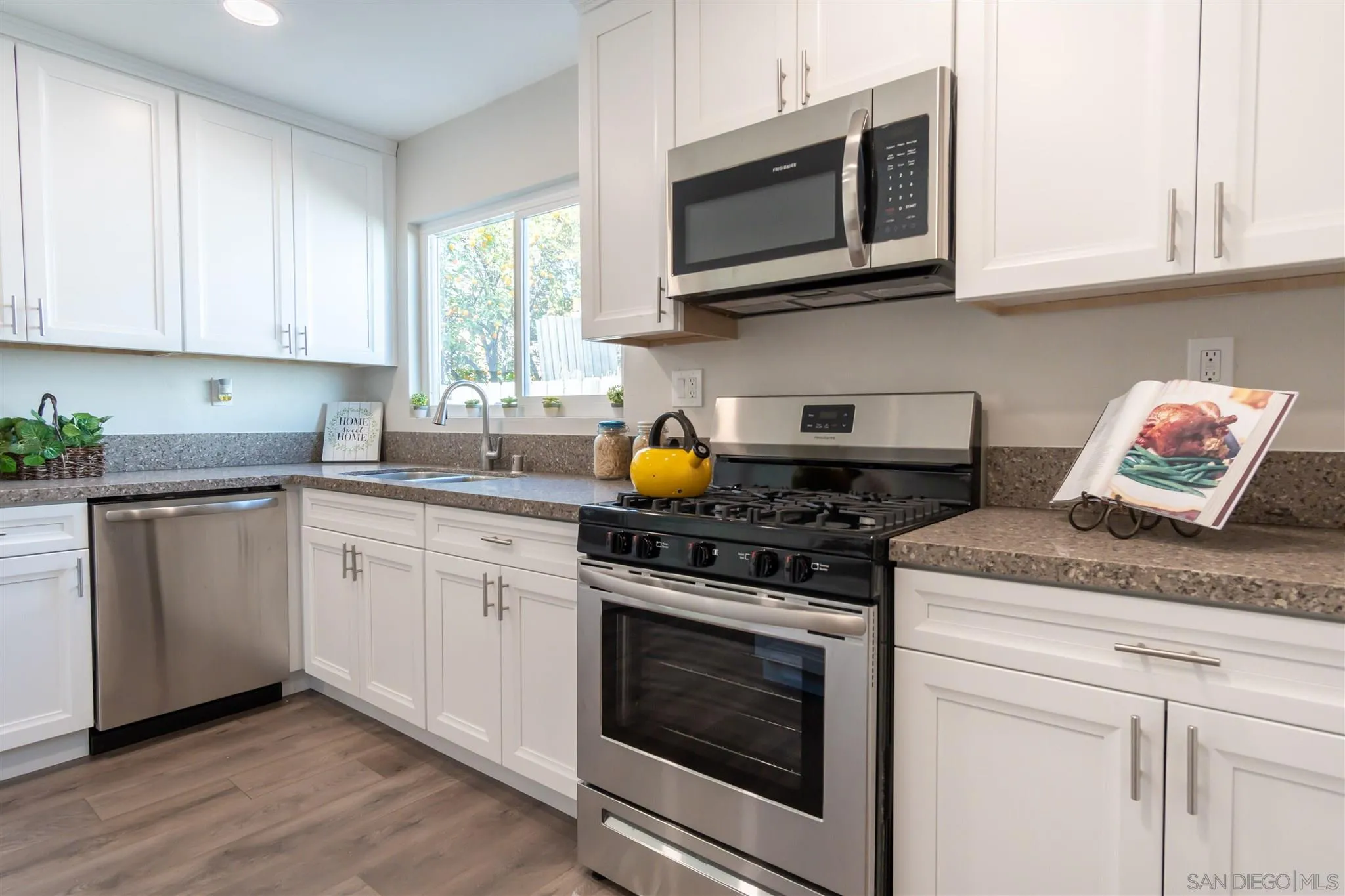 466 Cedar Street El Cajon, CA 92021 - Photo 10 of 26 a kitchen with stainless steel appliances granite countertop white cabinets granite counter tops and a wooden floors