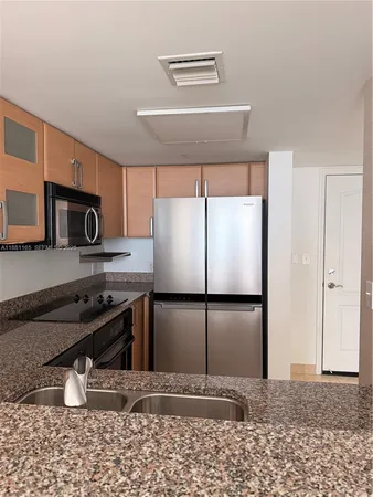a kitchen with granite countertop a refrigerator and a stove top oven