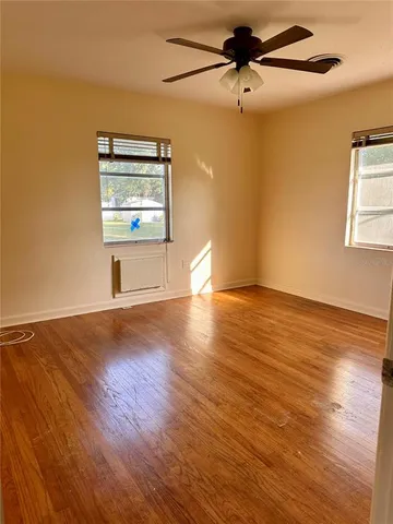 a view of empty room with wooden floor and fan