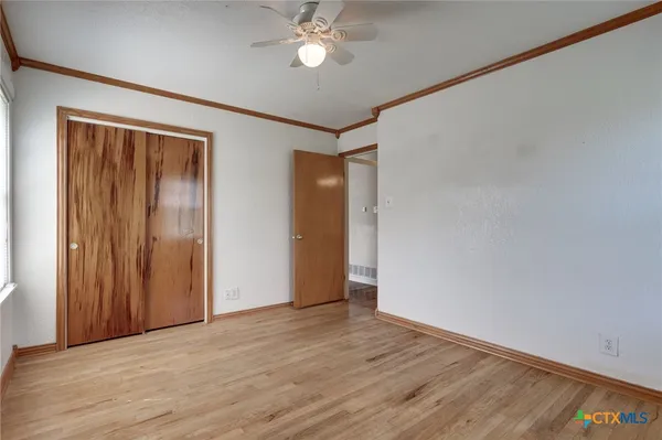 a view of an empty room with a window and wooden floor