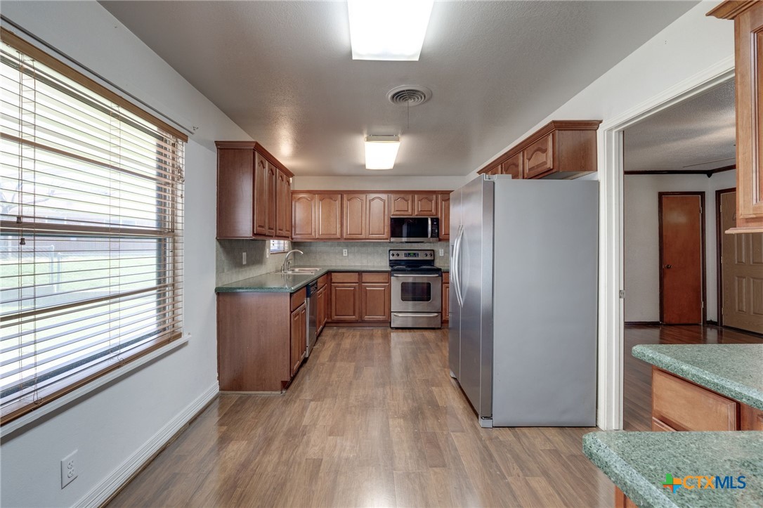 416 Cardinal Avenue Killeen, TX 76541 - Photo 7 of 18 a kitchen with stainless steel appliances granite countertop a refrigerator a sink dishwasher a stove and white countertops with wooden floor